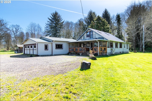 view of front of house with driveway, a porch, a front lawn, a garage, and metal roof