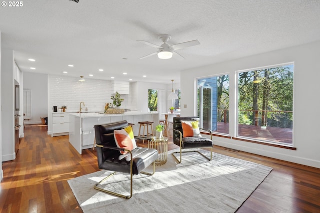 living area featuring a textured ceiling, wood finished floors, visible vents, and recessed lighting