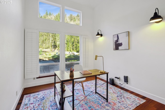 office area with a high ceiling, baseboards, and wood finished floors