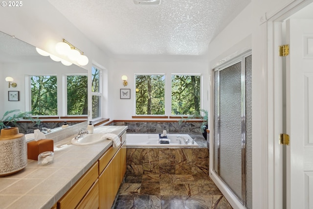 full bath featuring a bath, a shower stall, a textured ceiling, and vanity