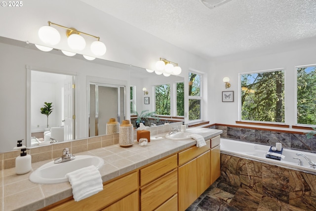 bathroom featuring a textured ceiling, a garden tub, a sink, a shower stall, and double vanity