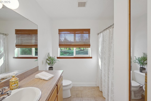 bathroom with visible vents, plenty of natural light, vanity, and toilet