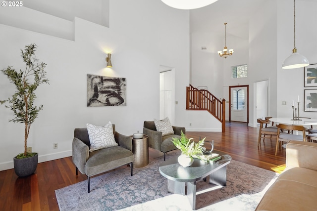 living area featuring stairs, a chandelier, wood finished floors, and baseboards