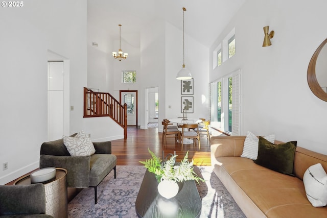 living area featuring stairs, a notable chandelier, baseboards, and wood finished floors