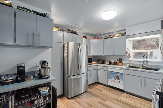 kitchen with stainless steel appliances, sink, light hardwood / wood-style floors, and gray cabinets