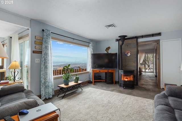 living room featuring a healthy amount of sunlight, concrete flooring, and a wood stove