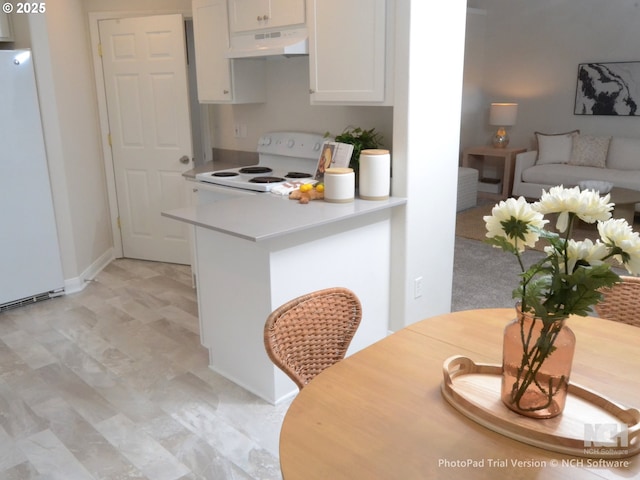 kitchen featuring white cabinets, light countertops, white appliances, under cabinet range hood, and light floors