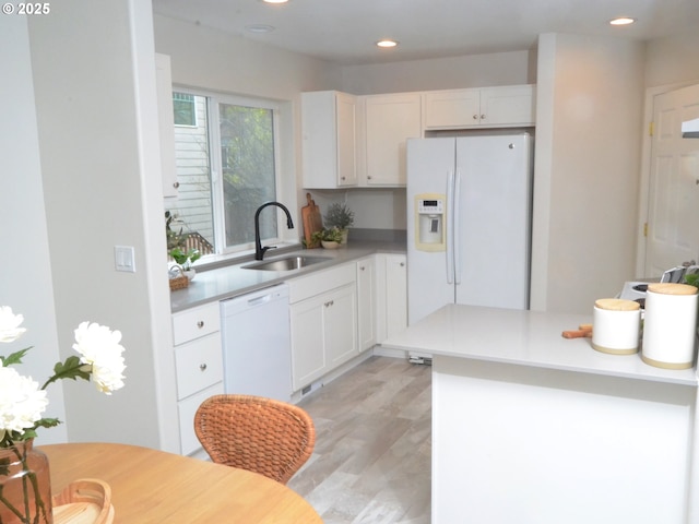 kitchen with light wood-style floors, white appliances, white cabinets, light countertops, and a sink