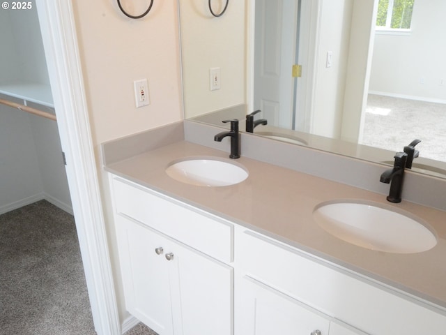 bathroom with double vanity, a sink, and baseboards