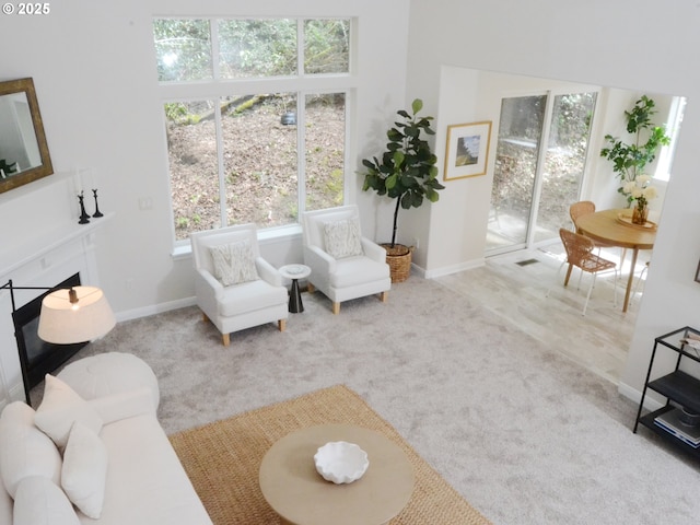 living area featuring a fireplace, baseboards, and carpet floors