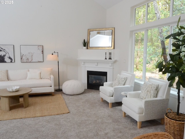 living area with carpet flooring, a glass covered fireplace, and vaulted ceiling