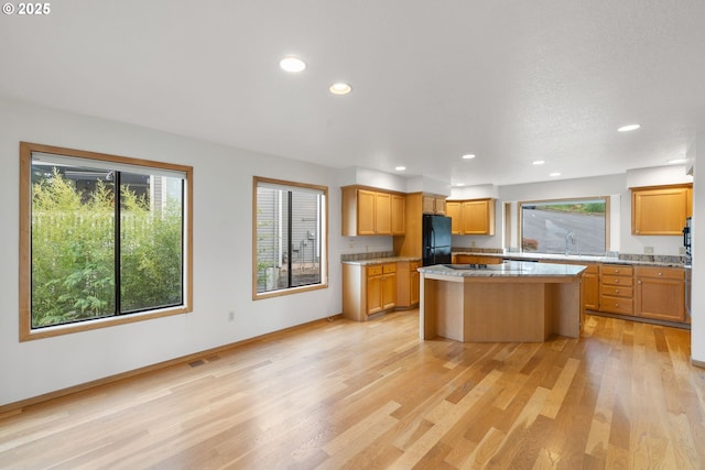 2305 Chickadee Ct, West Linn, OR 97068 - kitchen with black appliances, light wood-style flooring, a kitchen island, recessed lighting, and a sink