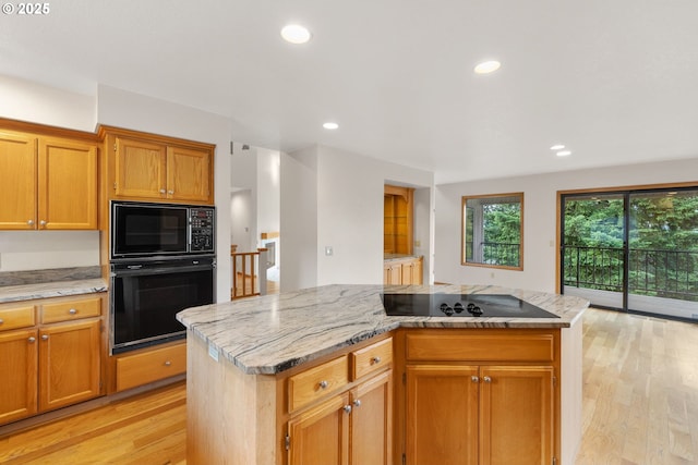 2305 Chickadee Ct, West Linn, OR 97068 - kitchen featuring black appliances, a kitchen island, light wood-style flooring, recessed lighting, and light stone counters