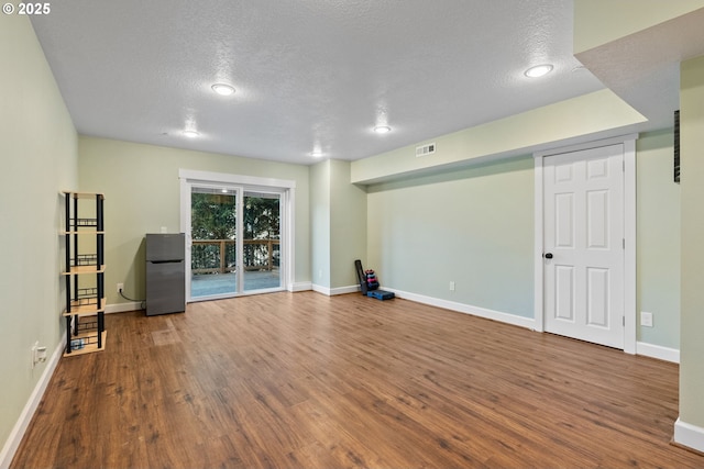 interior space featuring visible vents, baseboards, a textured ceiling, and wood finished floors