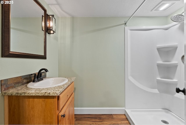 bathroom featuring baseboards, vanity, wood finished floors, and a shower stall