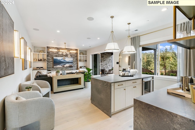 kitchen with light wood-style flooring, beverage cooler, a fireplace, white cabinetry, and open floor plan