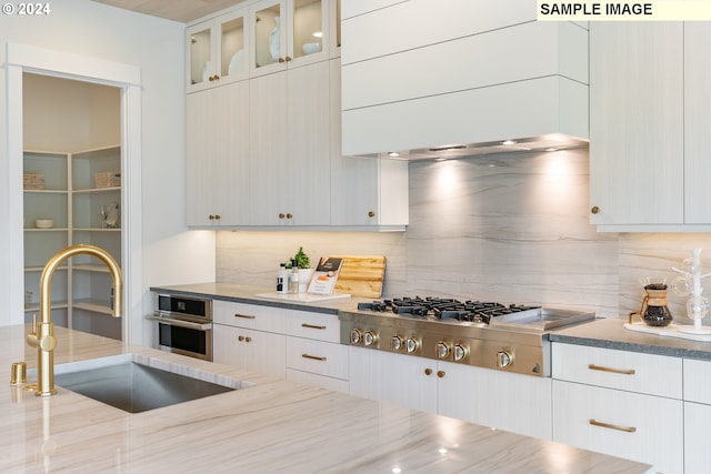 kitchen with glass insert cabinets, white cabinets, stainless steel appliances, and a sink