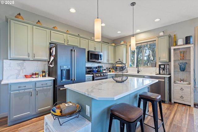 kitchen with hanging light fixtures, light wood finished floors, a breakfast bar, and stainless steel appliances