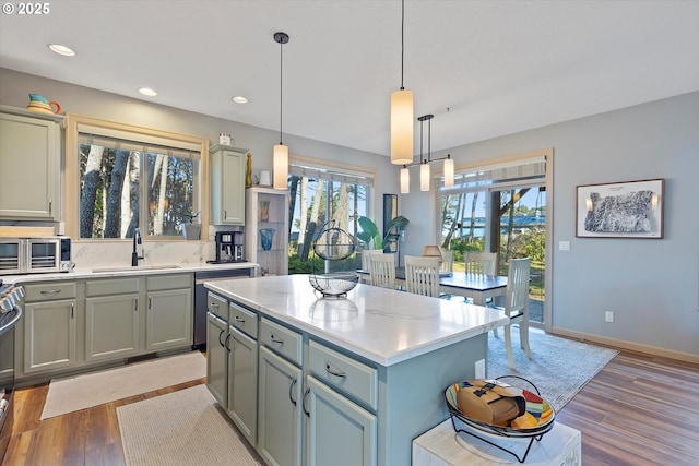 kitchen with baseboards, recessed lighting, light wood-style flooring, decorative light fixtures, and a sink