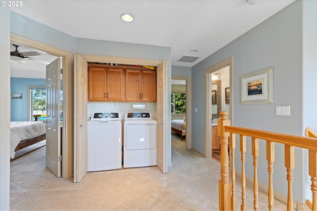 laundry area with visible vents, light carpet, a healthy amount of sunlight, washing machine and dryer, and cabinet space