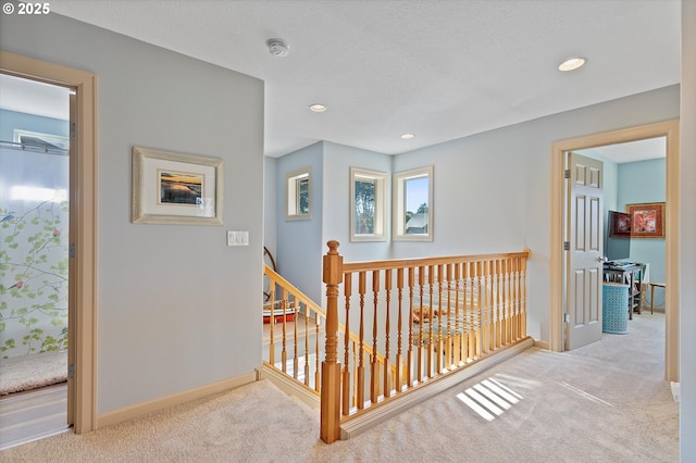 hall featuring baseboards, an upstairs landing, a textured ceiling, recessed lighting, and carpet flooring