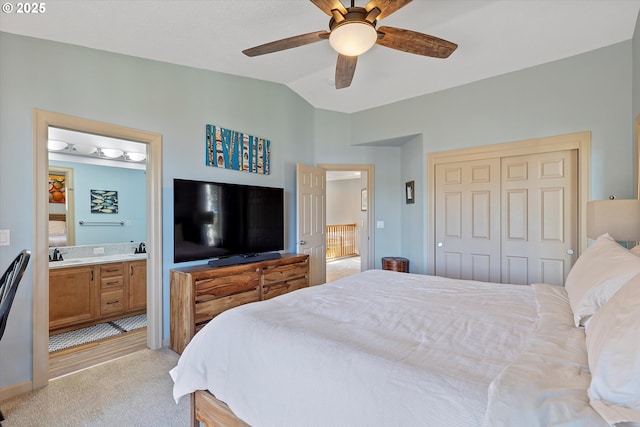 bedroom featuring a closet, ensuite bath, a ceiling fan, vaulted ceiling, and light carpet