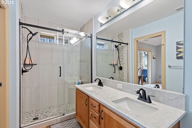 bathroom featuring visible vents, a sink, and a stall shower