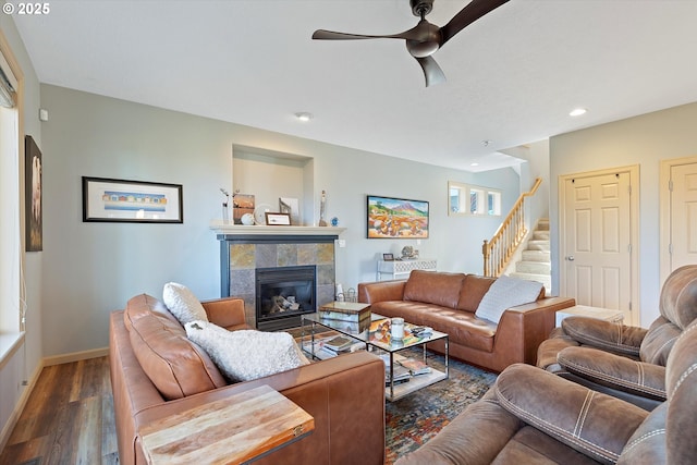 living room with baseboards, a ceiling fan, a fireplace, wood finished floors, and stairs