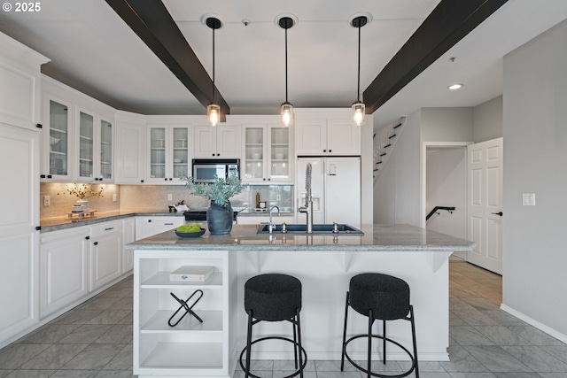 kitchen featuring decorative backsplash, stainless steel microwave, beamed ceiling, and open shelves