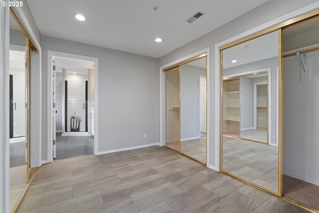 unfurnished bedroom with visible vents, two closets, ensuite bath, recessed lighting, and baseboards