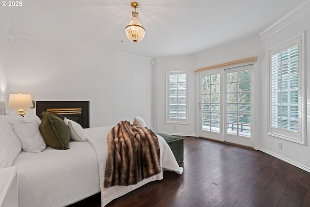 bedroom with access to exterior, a glass covered fireplace, dark wood-style floors, and ornamental molding