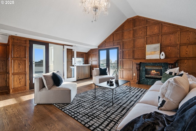 living area featuring a notable chandelier, wood finished floors, wood walls, and a high end fireplace