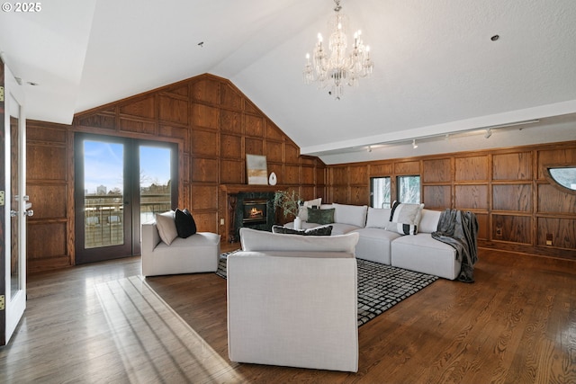 living area featuring wood finished floors, a healthy amount of sunlight, wood walls, and vaulted ceiling