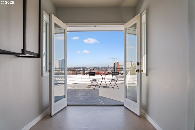 doorway featuring finished concrete floors, french doors, a view of city, and baseboards