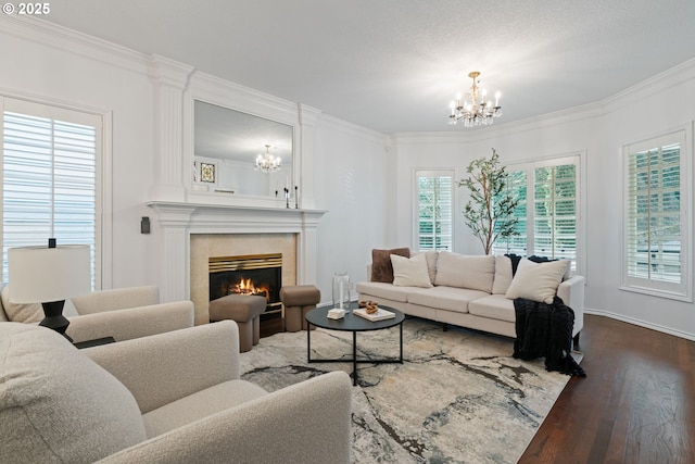 living room featuring a chandelier, dark wood-style floors, a fireplace, and ornamental molding