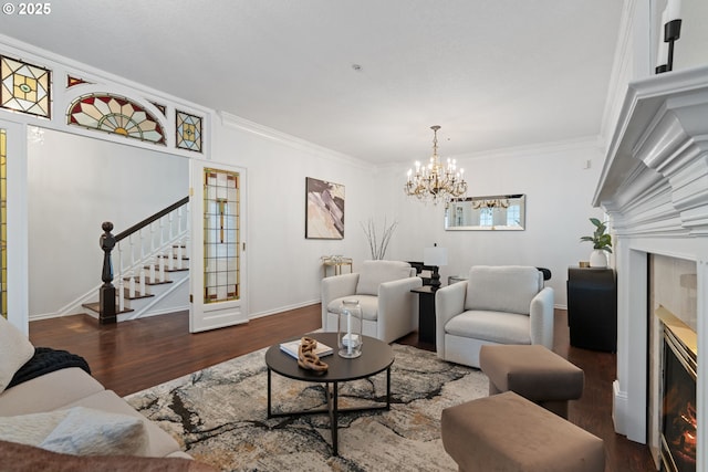 living room featuring a notable chandelier, ornamental molding, wood finished floors, a glass covered fireplace, and stairway