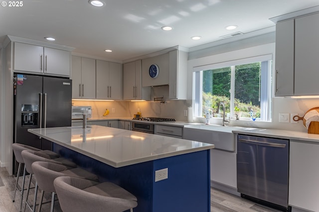 kitchen with appliances with stainless steel finishes, light wood-style floors, light countertops, recessed lighting, and a kitchen bar
