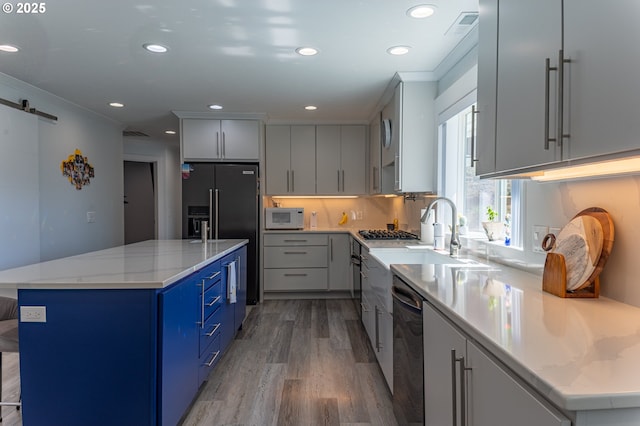 kitchen featuring white microwave, light wood finished floors, dishwashing machine, a sink, and high end fridge