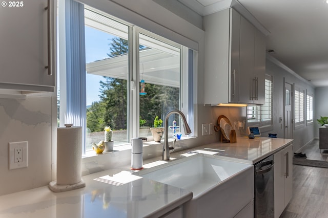kitchen featuring a sink, light wood-style flooring, gray cabinets, light countertops, and dishwasher