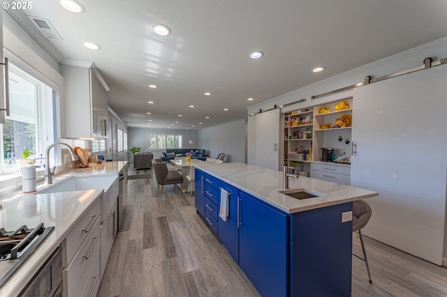 kitchen featuring a sink, blue cabinetry, light wood-type flooring, recessed lighting, and open floor plan