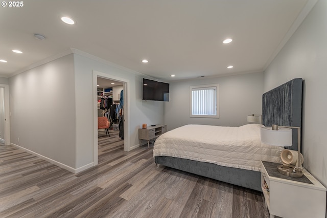 bedroom with crown molding, light wood-style flooring, a spacious closet, recessed lighting, and baseboards