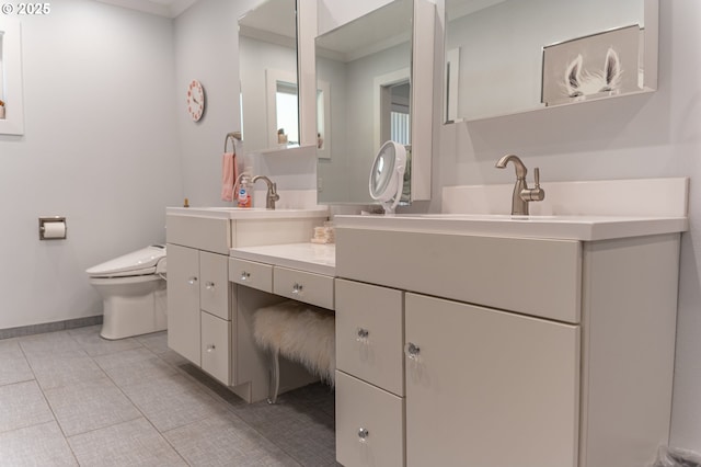 bathroom featuring toilet, crown molding, vanity, tile patterned floors, and baseboards
