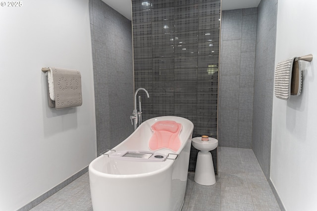 full bath with a soaking tub, tile patterned flooring, and baseboards