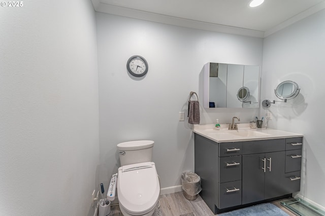 half bath with wood finished floors, vanity, baseboards, and toilet