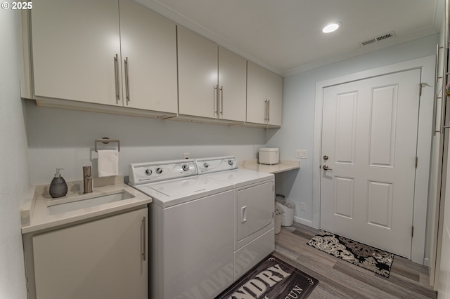 laundry room with separate washer and dryer, cabinet space, light wood-style floors, ornamental molding, and recessed lighting