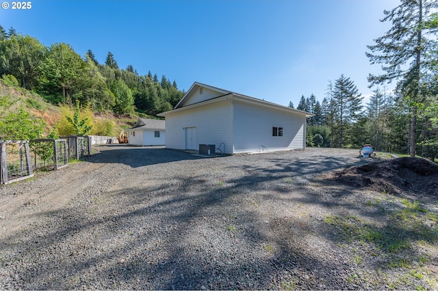 view of side of home with driveway, fence, and central AC