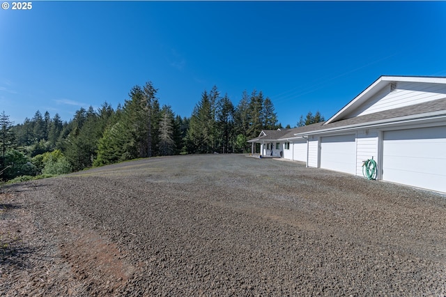 view of dirt / gravel driveway with a wooded view