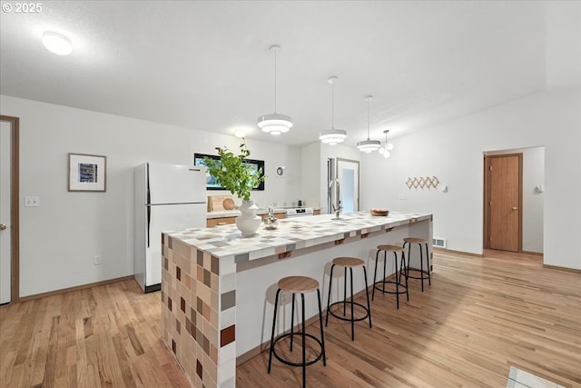 80487 Sha Ne Mah Rd, Seaside, OR 97138 - kitchen with freestanding refrigerator, light wood finished floors, a breakfast bar, and a large island