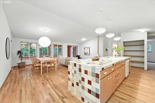 80487 Sha Ne Mah Rd, Seaside, OR 97138 - kitchen with light wood-type flooring, vaulted ceiling, a large island with sink, and hanging light fixtures