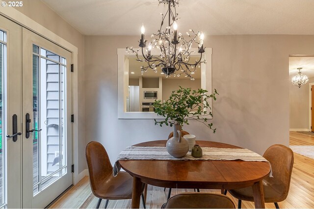 dining area with light wood-style floors, baseboards, and a notable chandelier